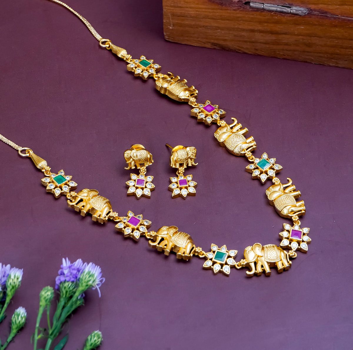 Gold elephant motif necklace set with colorful gemstone accents and matching earrings