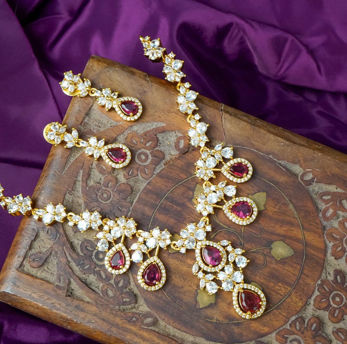 Gold floral necklace set with ruby teardrop stones and matching earrings